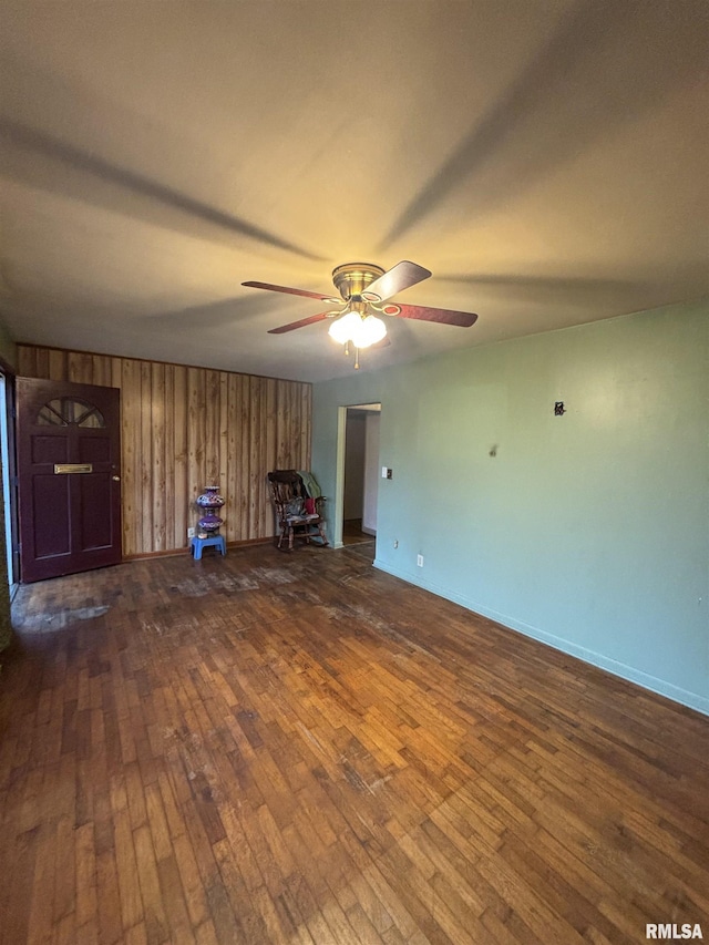 empty room with wooden walls, dark hardwood / wood-style flooring, and ceiling fan