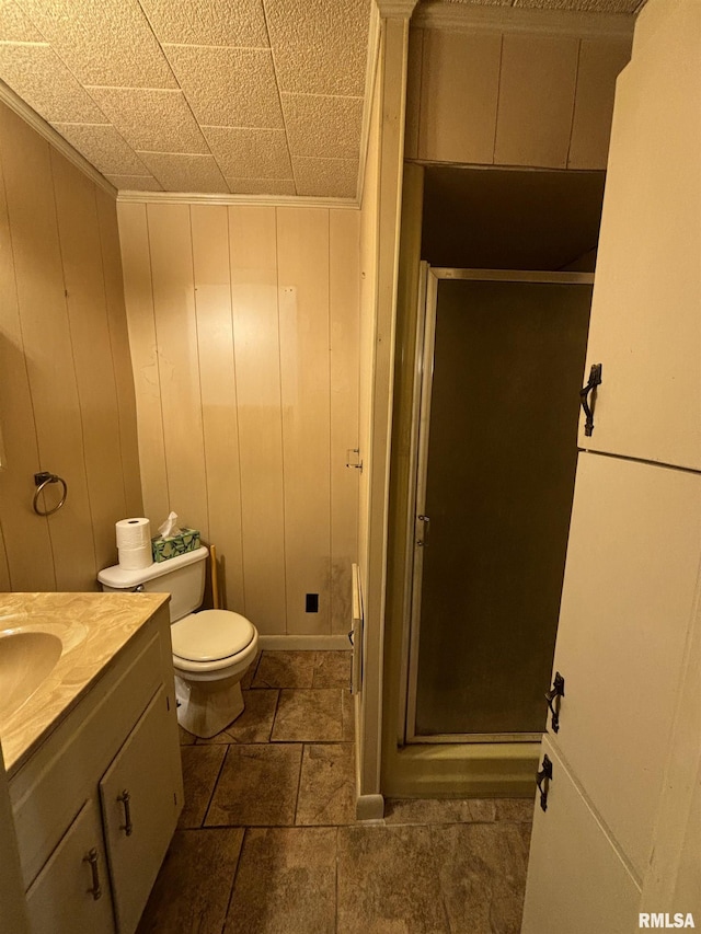 bathroom with an enclosed shower, vanity, tile patterned flooring, toilet, and wood walls