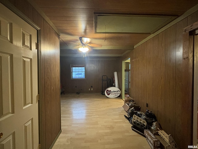 hall featuring light wood-type flooring and wooden walls