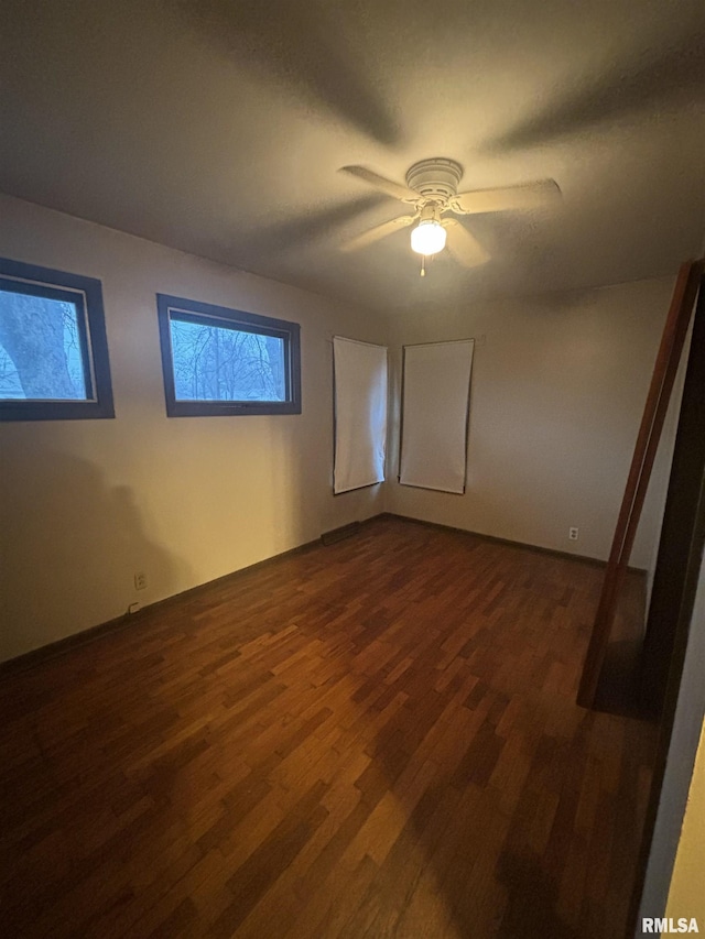 empty room with ceiling fan and dark wood-type flooring