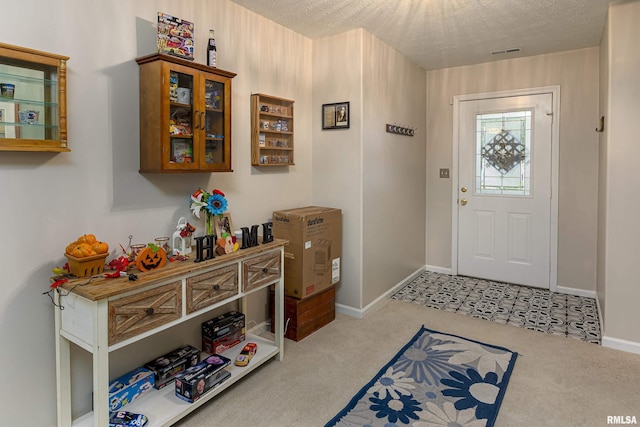 carpeted foyer entrance with a textured ceiling