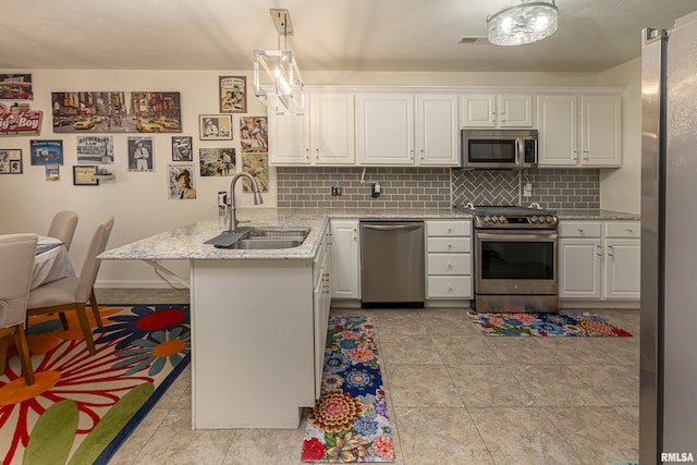 kitchen featuring kitchen peninsula, stainless steel appliances, sink, decorative light fixtures, and white cabinetry