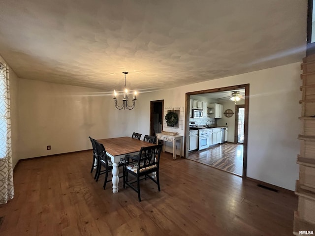 dining room with hardwood / wood-style floors and ceiling fan with notable chandelier