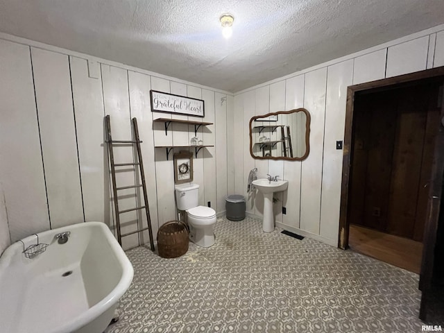 bathroom featuring sink, a washtub, a textured ceiling, and toilet