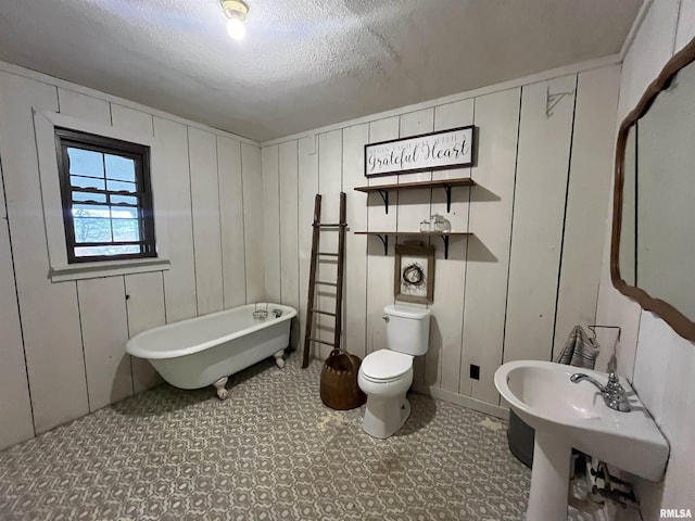 bathroom featuring a textured ceiling, toilet, and a bathtub