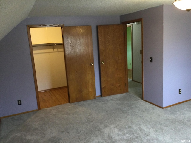 unfurnished bedroom featuring light colored carpet, a spacious closet, vaulted ceiling, and a closet