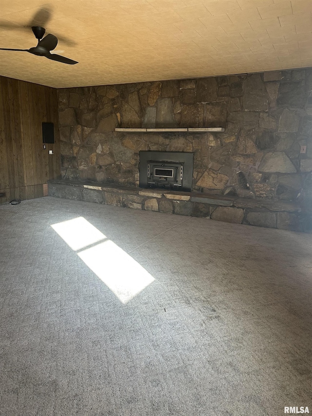 unfurnished living room featuring carpet flooring, ceiling fan, and wood walls