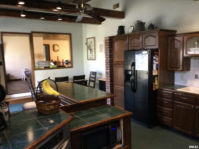 kitchen featuring ceiling fan, tile countertops, black appliances, sink, and dark brown cabinetry