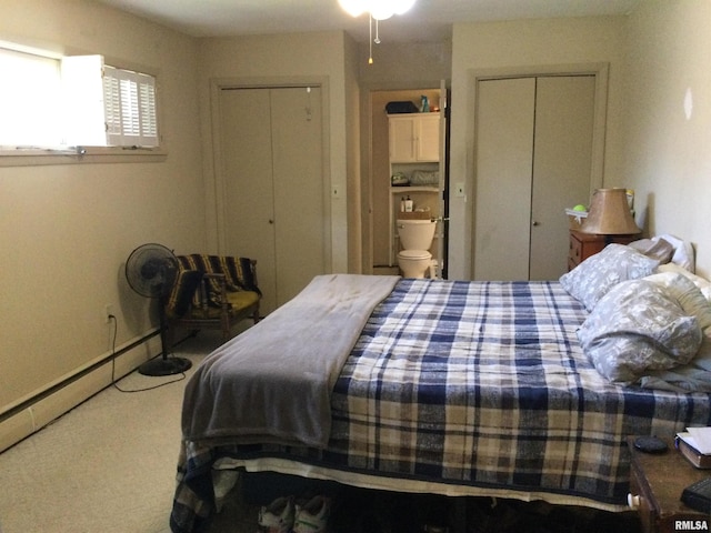 bedroom featuring a baseboard heating unit and two closets