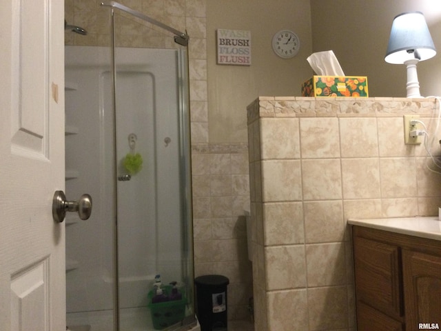 bathroom featuring vanity, tile walls, and a shower with door