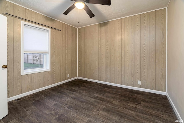 spare room featuring dark hardwood / wood-style floors, ceiling fan, and wooden walls