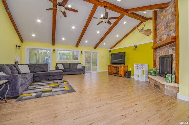 living room featuring beam ceiling, a stone fireplace, high vaulted ceiling, and light hardwood / wood-style flooring