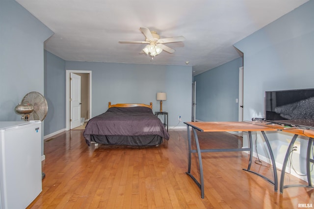 bedroom featuring fridge, light hardwood / wood-style flooring, and ceiling fan