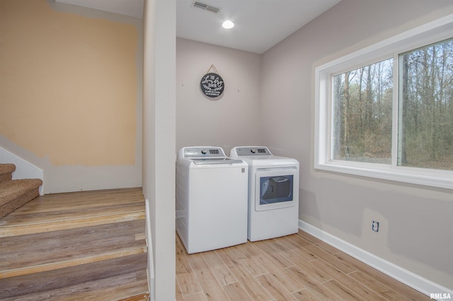 washroom with washing machine and dryer and light hardwood / wood-style floors