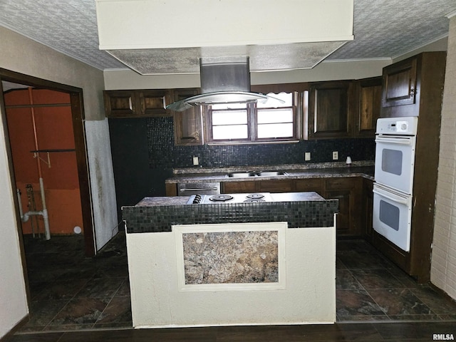 kitchen featuring decorative backsplash, a textured ceiling, white double oven, and island range hood