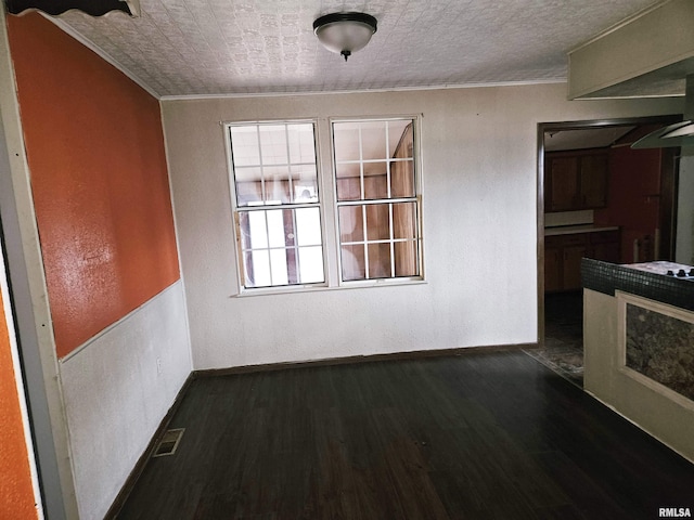 unfurnished dining area featuring dark hardwood / wood-style floors and ornamental molding