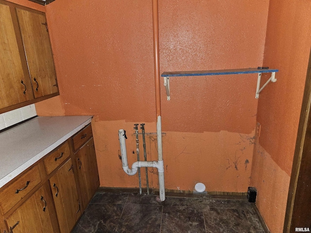 laundry room with dark tile patterned floors and cabinets