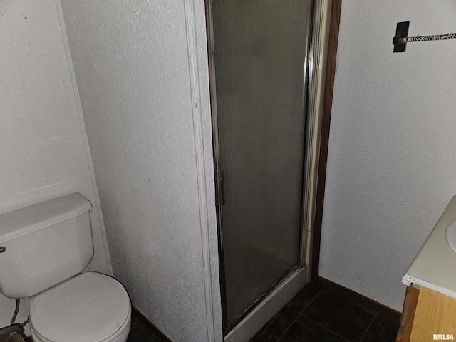 bathroom with tile patterned flooring, vanity, toilet, and walk in shower