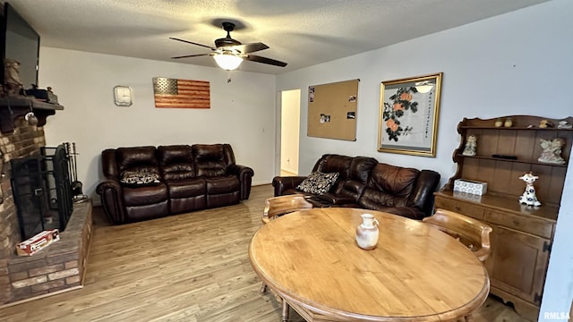 1807 E Saint Louis St, West Frankfort, IL 62896 - living room featuring a brick fireplace, ceiling fan, light wood-type flooring, and a textured ceiling