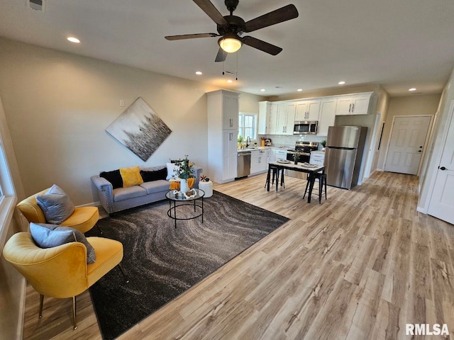 living area with recessed lighting, a ceiling fan, and light wood finished floors