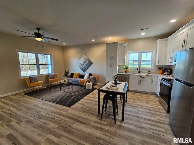 kitchen with light wood-type flooring, visible vents, open floor plan, and stainless steel appliances