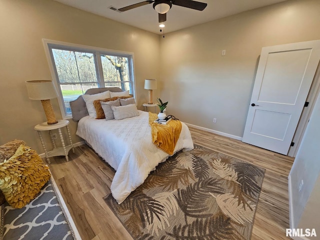 bedroom featuring a ceiling fan, light wood-style flooring, baseboards, and visible vents