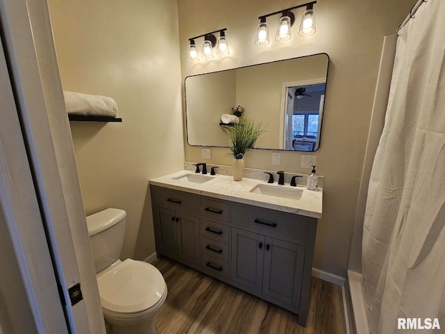 bathroom featuring a sink, toilet, wood finished floors, and double vanity