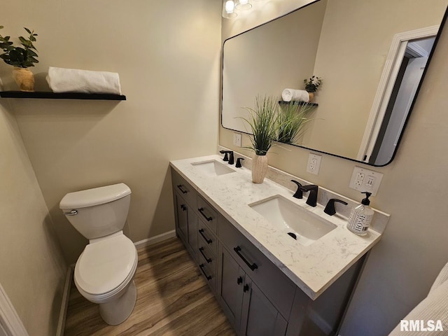 bathroom featuring double vanity, toilet, wood finished floors, and a sink