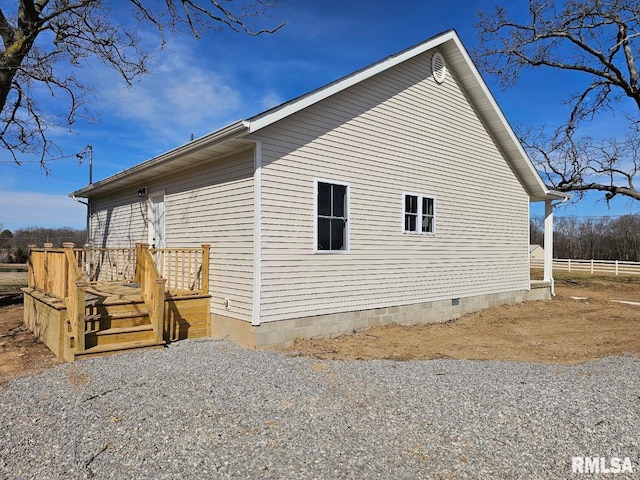 view of side of home featuring a deck, fence, and crawl space