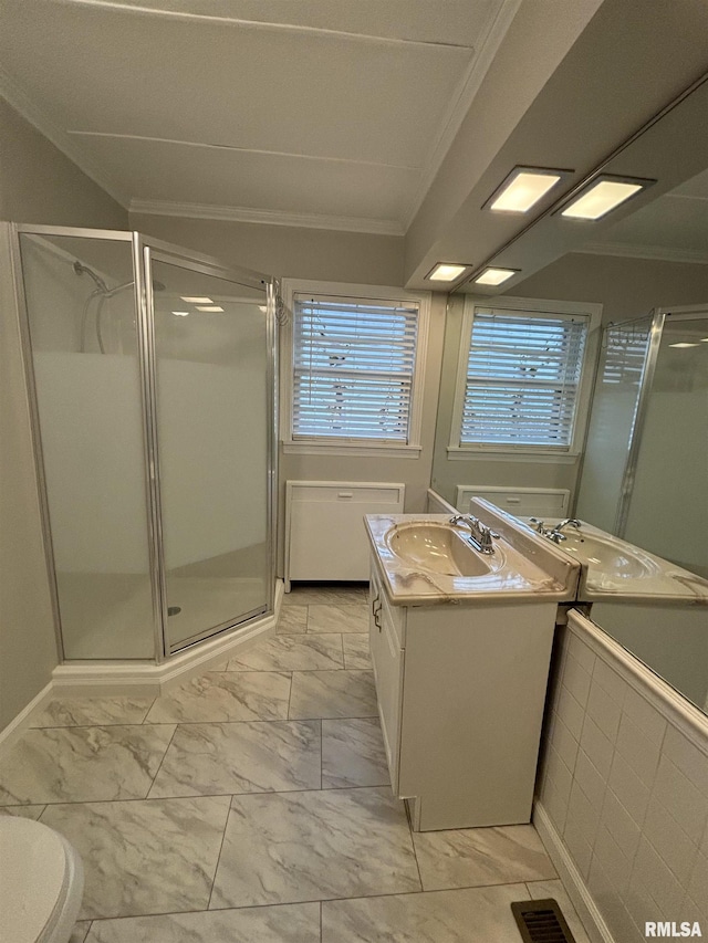 bathroom featuring a shower with door, vanity, a healthy amount of sunlight, and ornamental molding