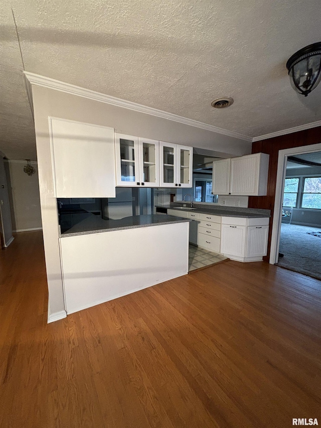 kitchen with white cabinets, a textured ceiling, dark hardwood / wood-style floors, and crown molding