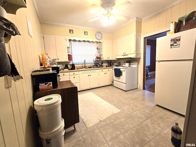 kitchen with wood walls, white appliances, sink, ceiling fan, and white cabinetry