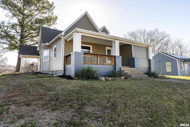 view of front of home with a porch, a front yard, and a shingled roof