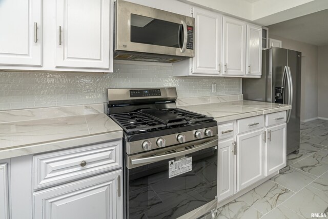 kitchen featuring decorative backsplash, light stone counters, white cabinetry, and appliances with stainless steel finishes