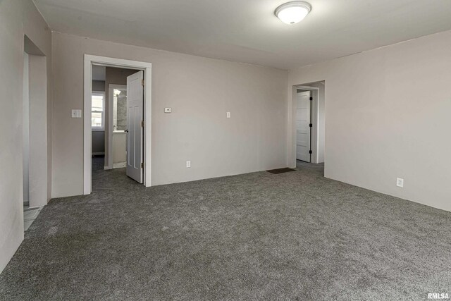 empty room featuring a wealth of natural light and dark colored carpet