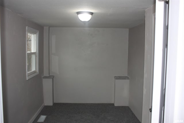 unfurnished room featuring dark colored carpet