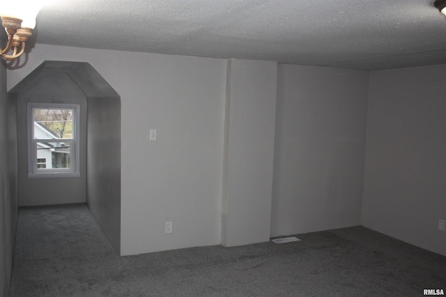 additional living space with dark colored carpet and a textured ceiling