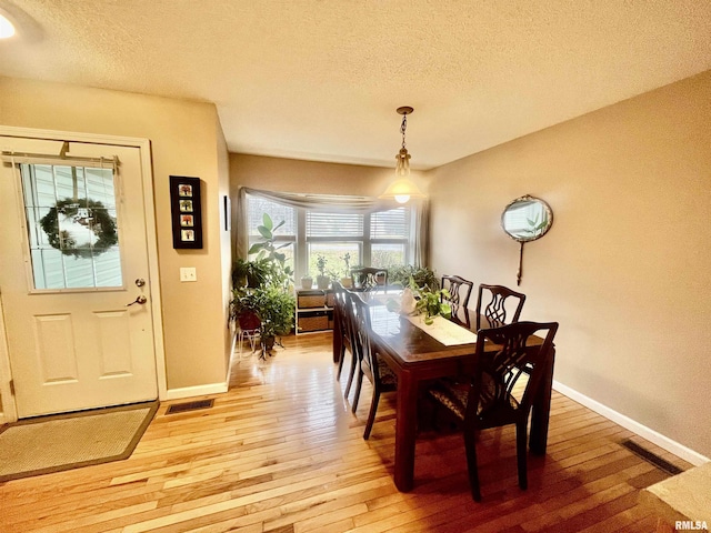 dining space featuring a textured ceiling and light hardwood / wood-style flooring