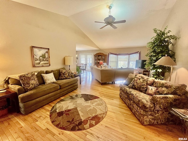 living room with ceiling fan, light hardwood / wood-style floors, and vaulted ceiling