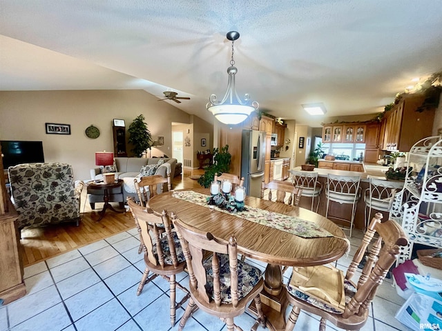 tiled dining area featuring ceiling fan, a textured ceiling, and vaulted ceiling