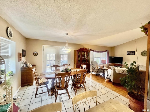 tiled dining area with vaulted ceiling, a textured ceiling, and french doors