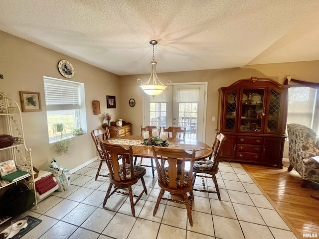 dining room with french doors, light tile patterned floors, and a textured ceiling