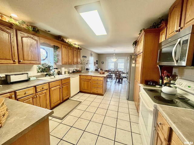 kitchen featuring kitchen peninsula, appliances with stainless steel finishes, decorative backsplash, sink, and pendant lighting