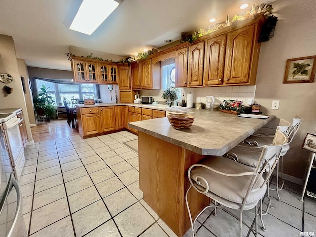 kitchen featuring kitchen peninsula, light tile patterned floors, a kitchen bar, and a healthy amount of sunlight