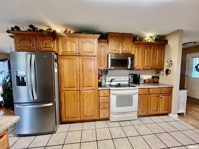 kitchen with backsplash, light tile patterned floors, and appliances with stainless steel finishes