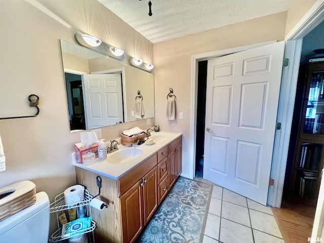 bathroom featuring tile patterned floors, vanity, a textured ceiling, and toilet