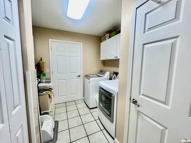 laundry area featuring washer and dryer, light tile patterned floors, cabinets, and a textured ceiling