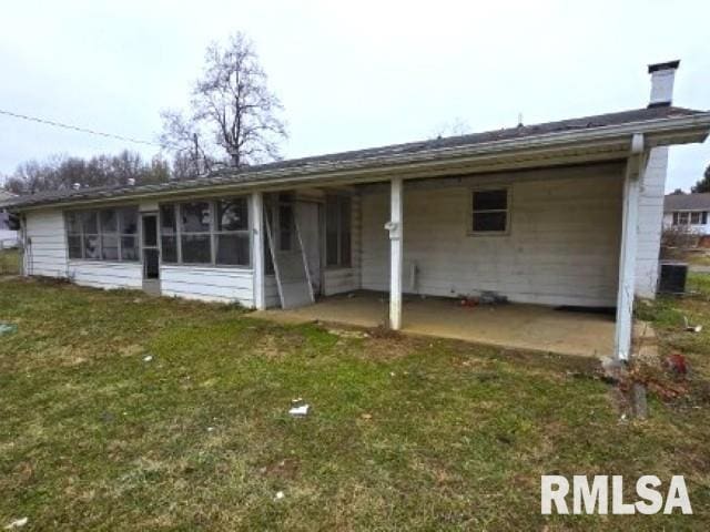 back of property featuring a lawn, a patio area, and a sunroom