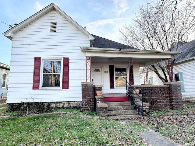 bungalow with covered porch, a front yard, and roof with shingles