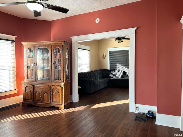 hallway featuring dark wood-style floors, a textured ceiling, and visible vents